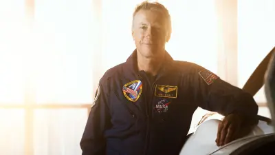 Michael Foale is leaning against a light aircraft in a hangar.