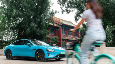 小米SU7行驶在高架上，背景高楼矗立。